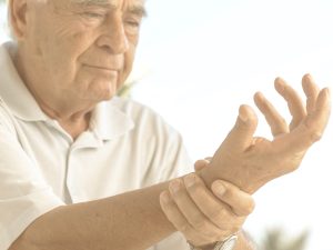 Primer plano de un hombre mayor que trata de mover los dedos mientras, con su otra mano, aferra su muñeca. La artrosis es una patología cuya incidencia aumenta con la edad y que afecta al cartílago de las articulaciones.  afecta sobre todo a algunos dedos de las manos y a las articulaciones que soportan mayor peso y realizan mayor esfuerzo como caderas, rodillas, hombros y las localizadas en las regiones cervical y lumbar de la columna.
