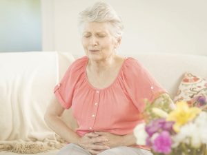 Las personas ancianas son más vulnerables a las infecciones urinarias, como la cistitis o la pielonefritis. En la imagen, vemos a una mujer mayor con las manos a la altura de la vegija y gesto de dolor.