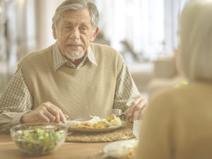 En la imagen, vemos un señor mayor comiendo junto a su mujer. En la mesa, observamos un bol de ensalada y un plato con variedad de color, lo que sugiere una dieta variada y equilibrada. Adaptar la alimentación a la edad y características de cada persona resulta fundamental para evitar problemas de salud y garantizar un buen aporte de nutrientes. Te ofrecemos algunas claves para llevar a cabo una correcta planificación semanal, así como un ejemplo de menú de otoño.