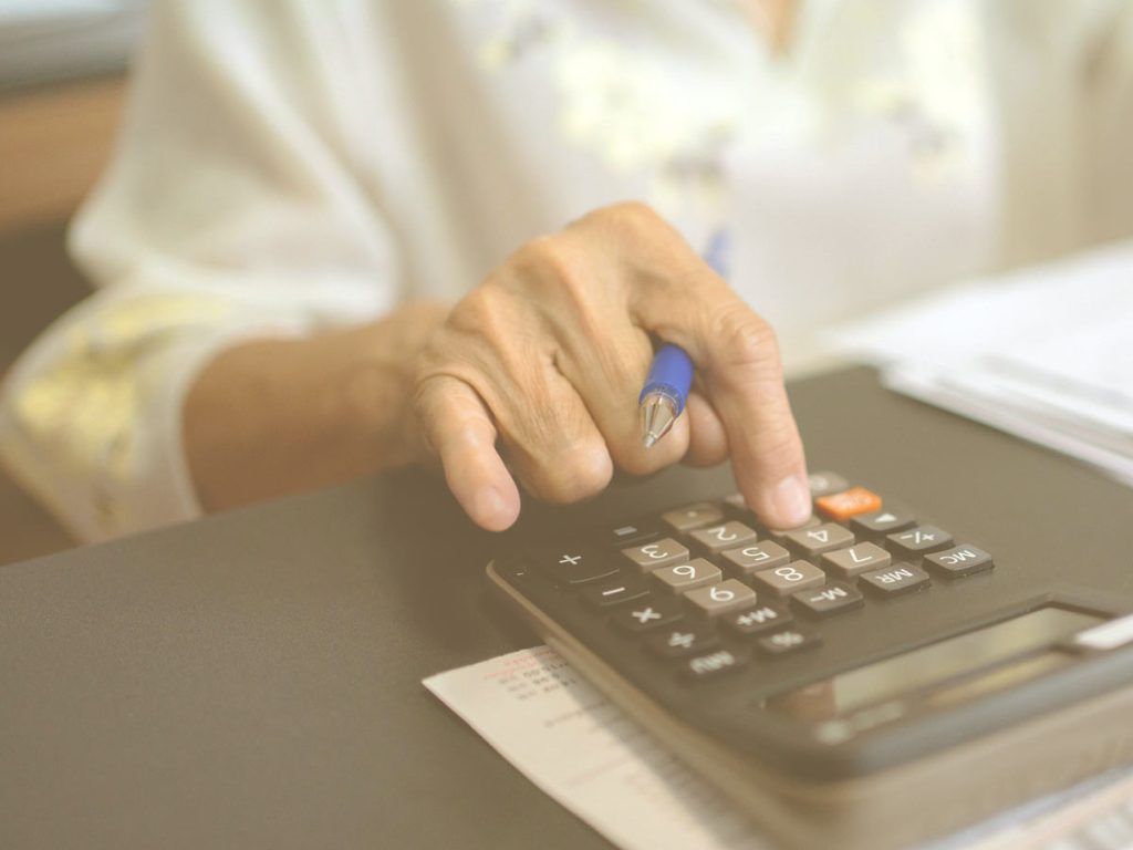 Cómo mejorar la capacidad cognitiva de las personas mayores a través de ejercicios de cálculo. En la imagen vemos la mano de una persona mayor utilizando una calculadora.