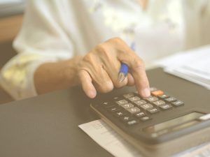Cómo mejorar la capacidad cognitiva de las personas mayores a través de ejercicios de cálculo. En la imagen vemos la mano de una persona mayor utilizando una calculadora.