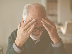 Síntomas del ictus: cómo reconocerlo y consejos prácticos para actuar si sufrimos un ictus o si lo sufre un familiar o persona cercana. En la imagen aparece un hombre anciano con las manos en la cabeza, en un claro signo de dolor.