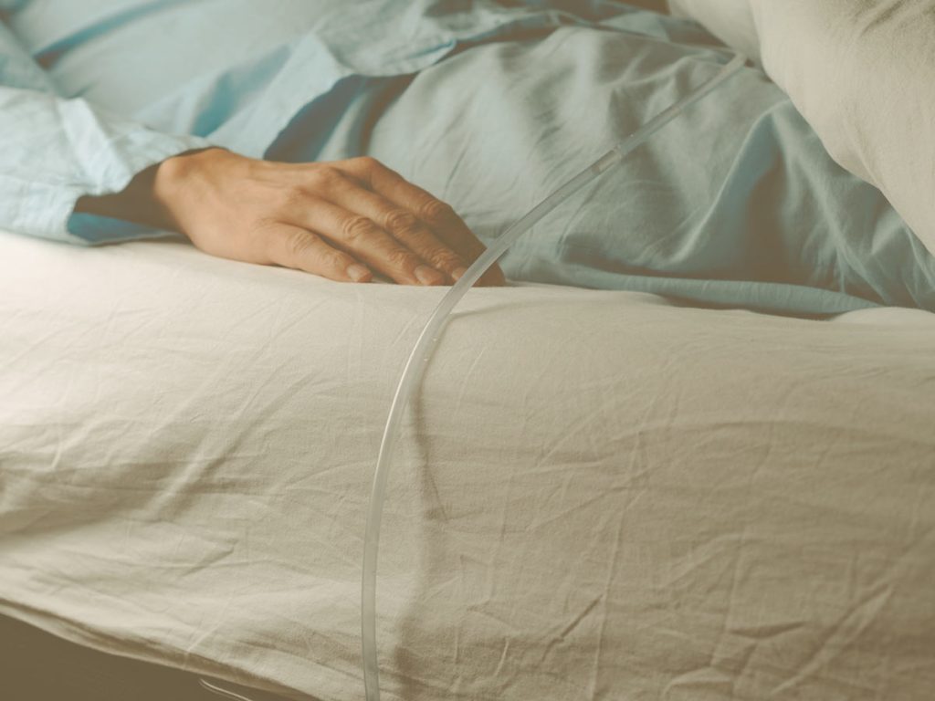Cómo cuidar a un familiar que tiene una sonda vesical: consejos de uso, limpieza y mantenimiento. En la imagen aparece una persona en la cama con una sonda vesical.